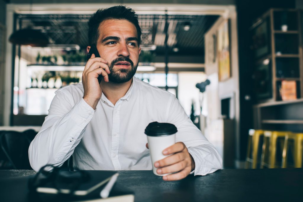 Stock photo of man drinking coffee getting a phone call
