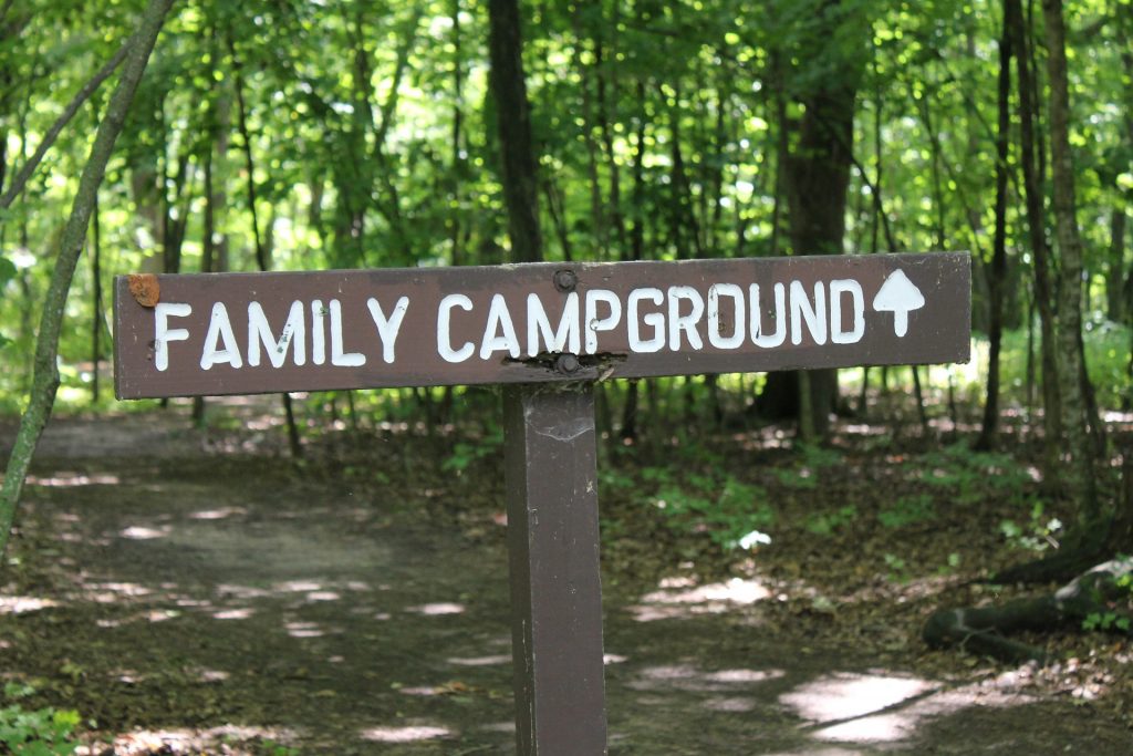 A painted wooden sign pointing the way toward the wooded family campground.