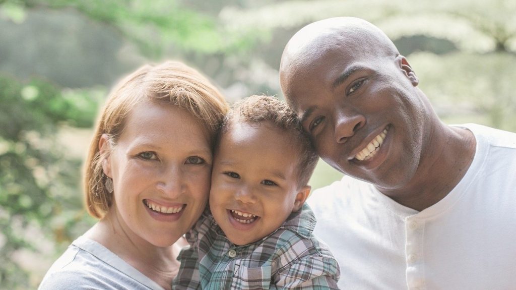 Mixed race couple holding children between them.