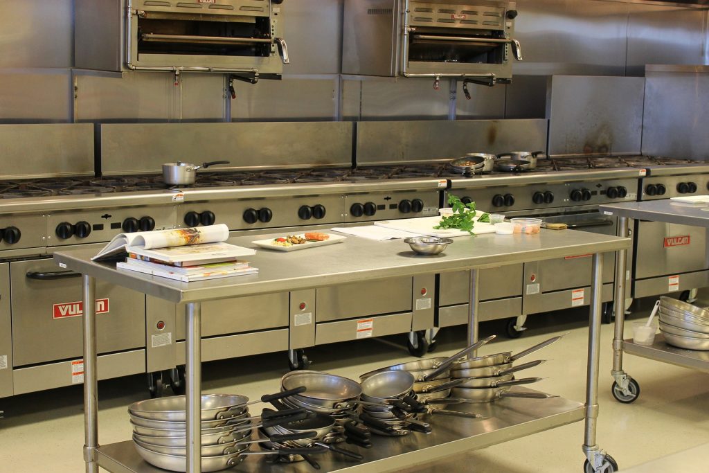 Stainless steel stoves, pans and table in a commercial kitchen