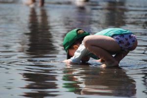 child drinking from a puddle