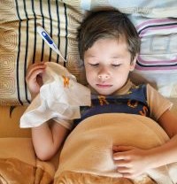 Sick baby with thermometer and tissue