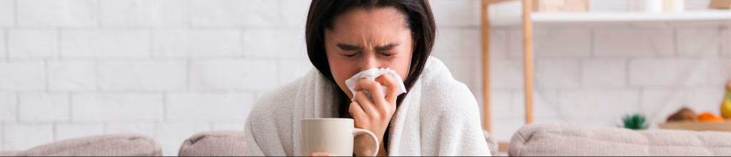 Photo of sneezing woman with tissue and mug