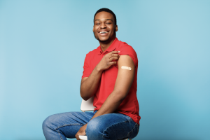 Photo of young African American male showing arm with bandaid where vaccination was received.