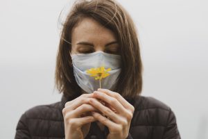 Woman in mask trying to smell a flower