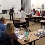 Attendees at tables provide input to facilitators who record the items on flip charts at the Comprehensive Opioid Abuse (CARA) Planning Grant Regional Mini-Cross Systems Mapping event.