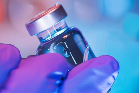 a small vaccine vial against a colorful background.
