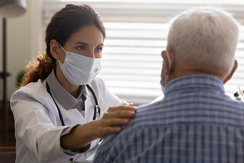 Un anciano es consolado por una doctora sobre las vacunas