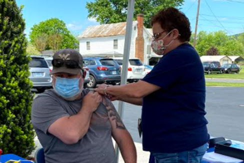 Un caballero mayor siendo vacunado contra el COVID-19 por una enfermera.