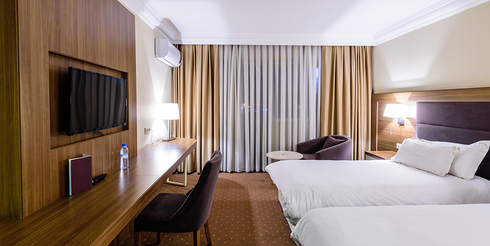 A clean hotel room with two beds and a desk area