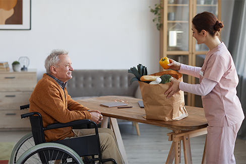 Un anciano recibe comida de una enfermera