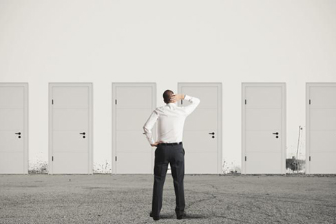 Hombre parado frente a las puertas frotándose la cabeza tratando de elegir.