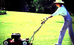 Lady wearing a hat mowing a yard
