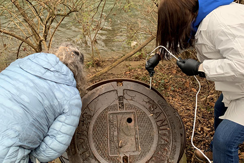 Two women lifting manhole cover