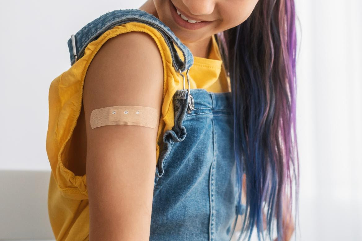Photo of young girl with a bandaid on her arm, showing that she has been vaccinated.