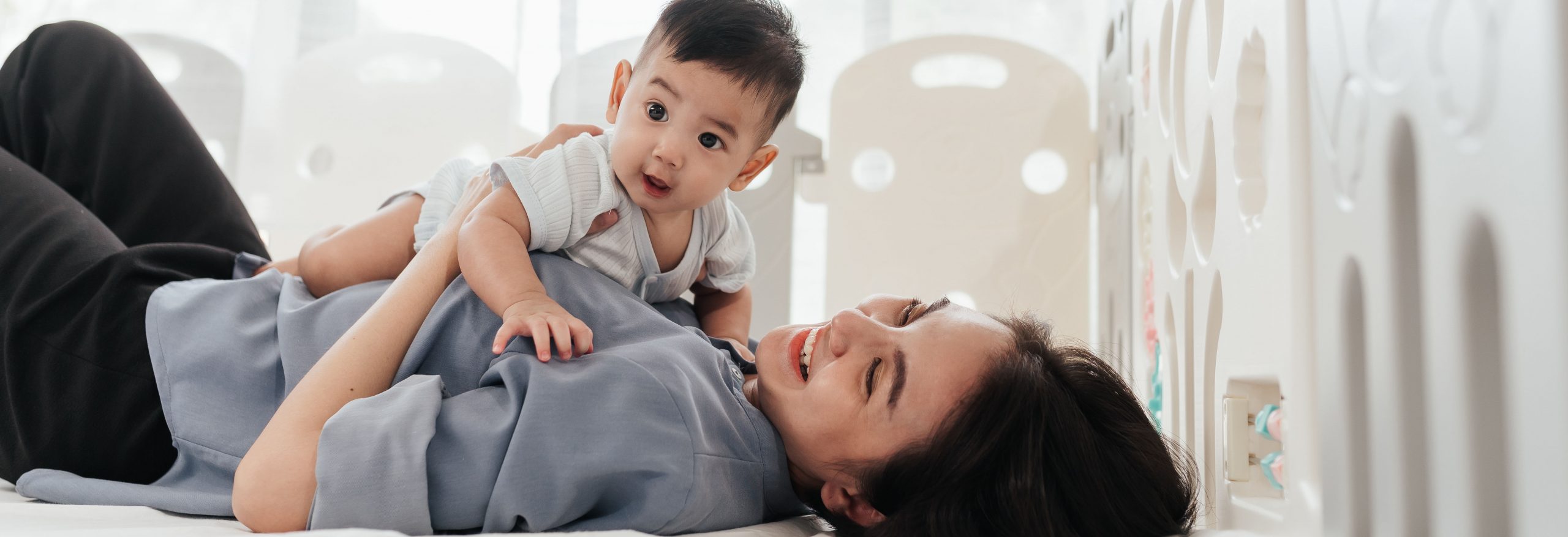 아시아의 사랑스러운 아기가 엄마와 함께 놀이를 즐기고 있습니다. 어린 아기를 안고 놀고 있는 동양인 엄마. 어버이날 콘셉트.