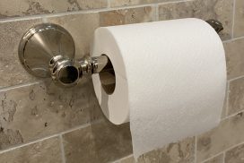 Roll of toilet paper on a beige tile wall