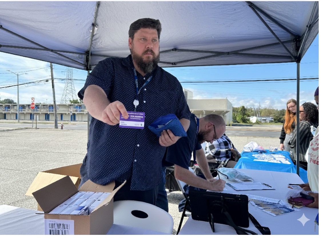 Photo of our Opioid Program Coordinator providing information to community member (off screen).