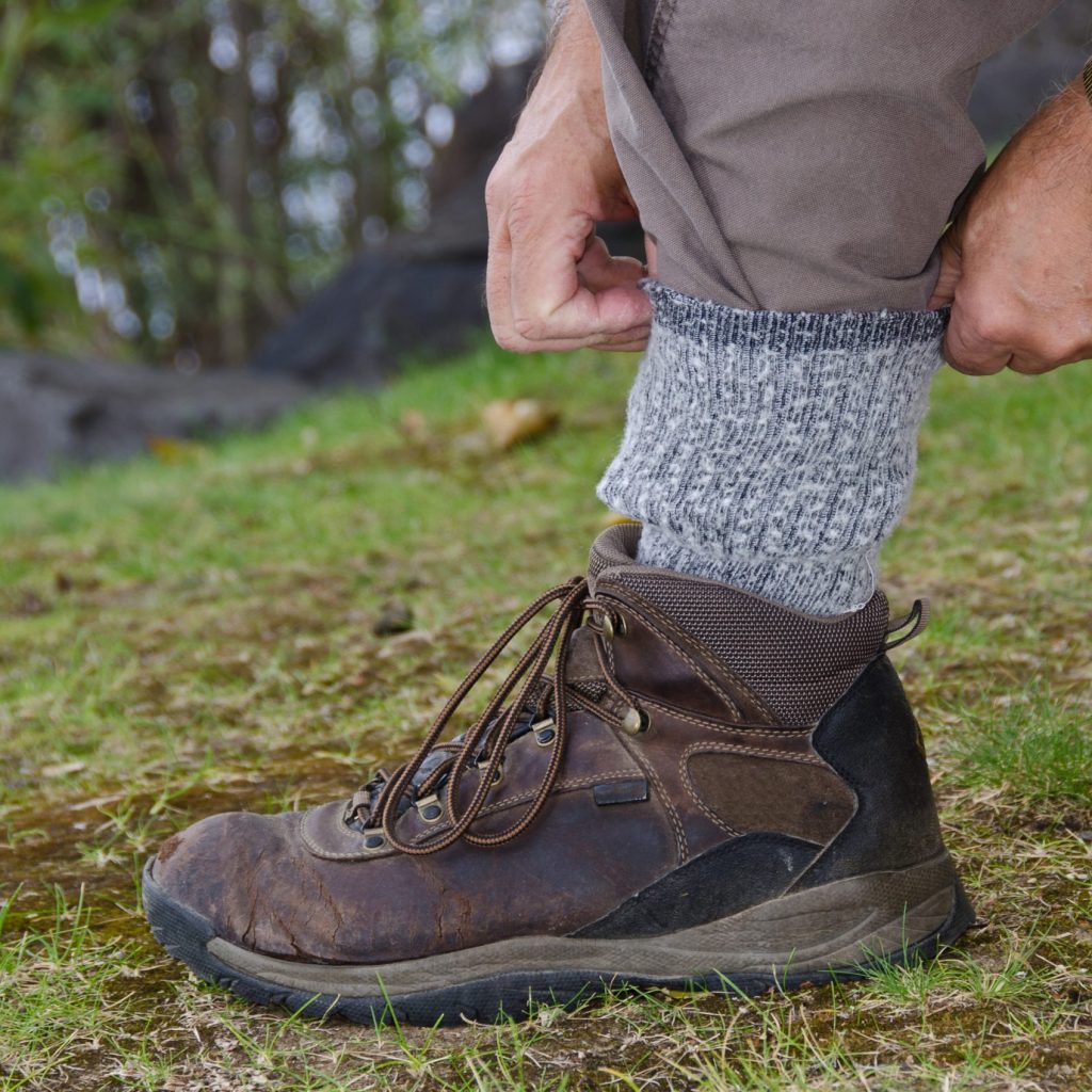 Photo of man tucking pant legs into socks to prevent tick bites.