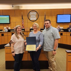 Picture of OEMS PSAP Specialist Amber Moore presenting Emergency Communications Manager Crystal Barton and Emergency Communications Supervisor Ethan Whaley with their OEMS EMD Accreditation certificate for Farmville