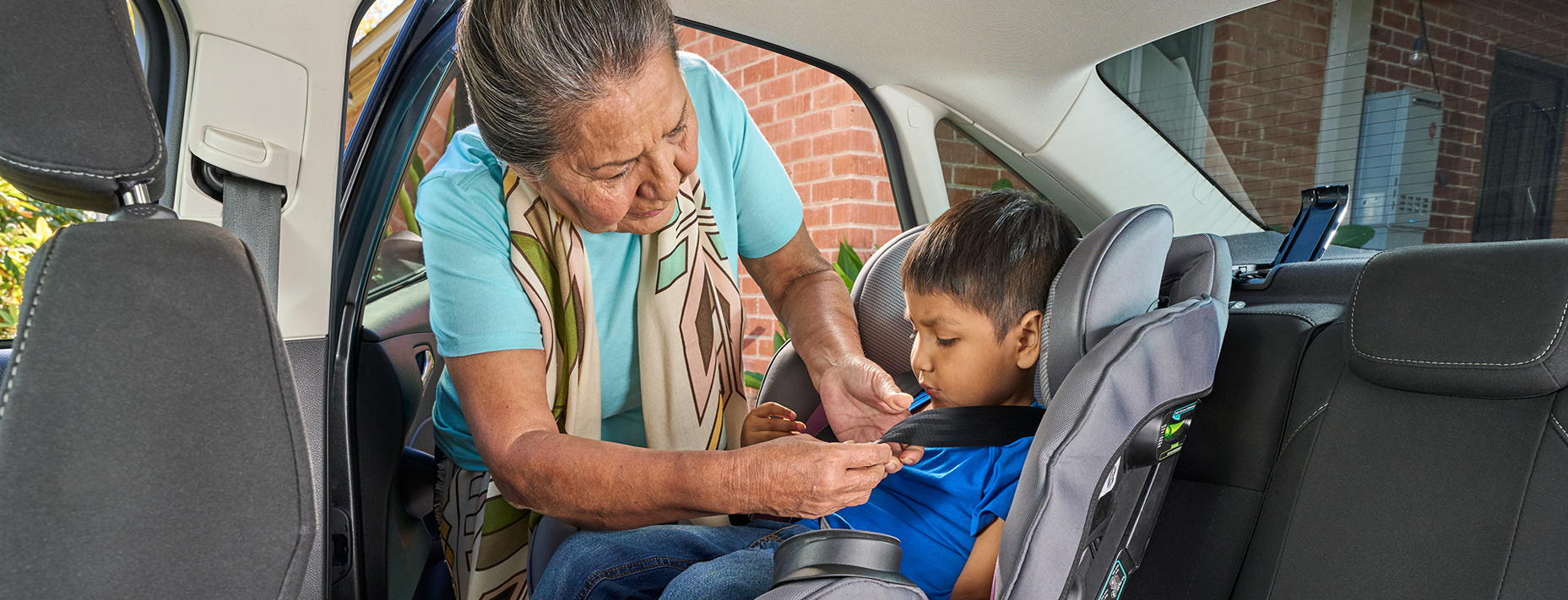 A woman fastening a child into a car seat