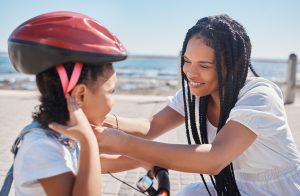 mom is putting helmet on daughter