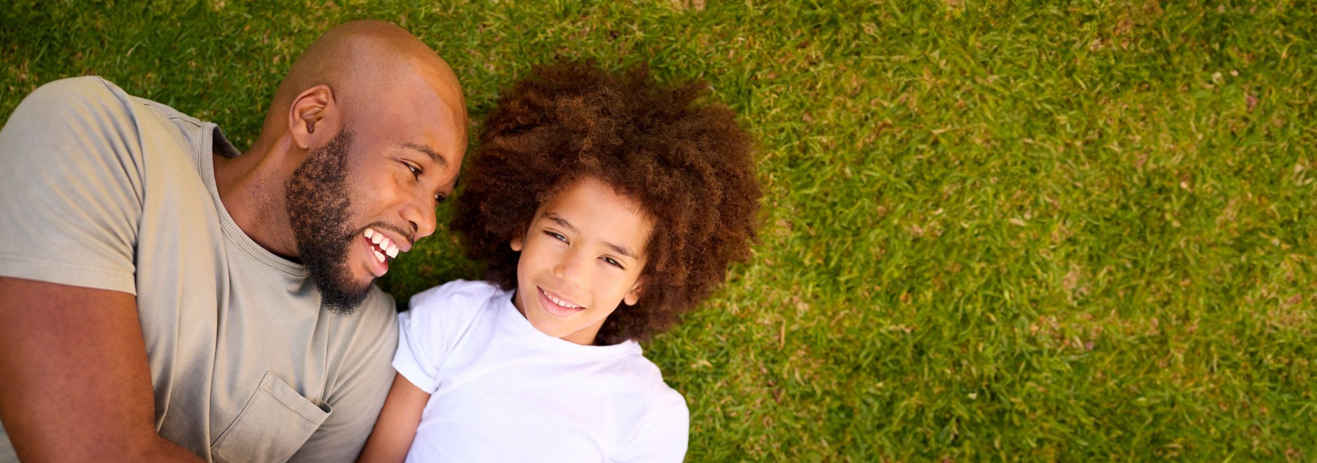 Overhead Shot Of Loving Father And Son Lying On Grass Together