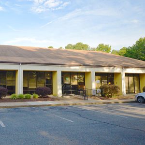 Un edificio amarillo de un piso con tejas color canela y columnas de marfil.