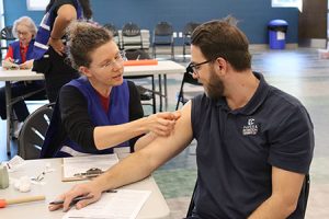 Một người băng bó cánh tay của người khác.