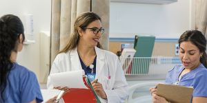 Một y tá đang nói chuyện với hai thực tập sinh trong phòng khám.