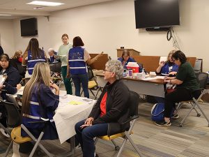 Patients sit at tables with health care workers.